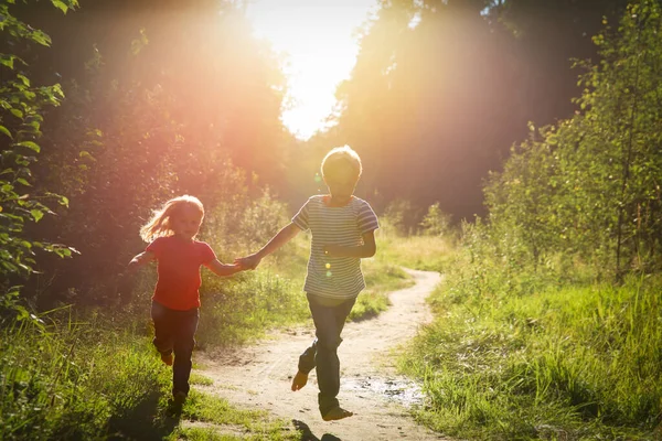 Menino e menina feliz correndo ao pôr do sol natureza — Fotografia de Stock