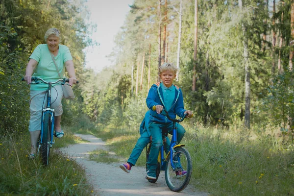 Abuela senior activa con niños montando bicicletas en la naturaleza — Foto de Stock