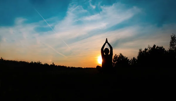 Силует молодого чоловіка робить йогу в природі заходу сонця — стокове фото