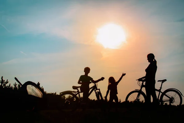 Gelukkig moeder met kinderen fietsen bij zonsondergang, familie oefening in de natuur — Stockfoto