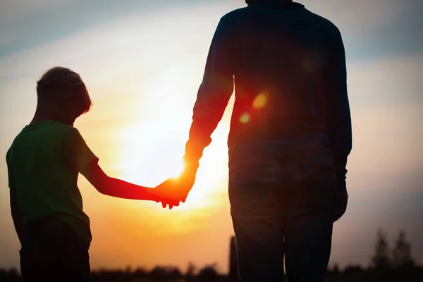 Silhouette von Vater und Sohn beim Händchenhalten bei Sonnenuntergang — Stockfoto