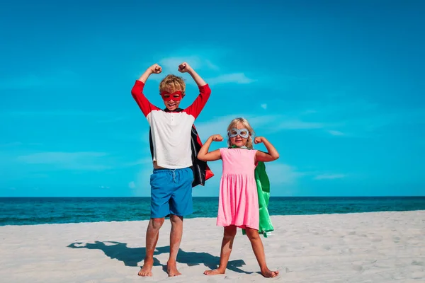 Fiú és lány játszani szuperhősök a strandon nyaralás — Stock Fotó