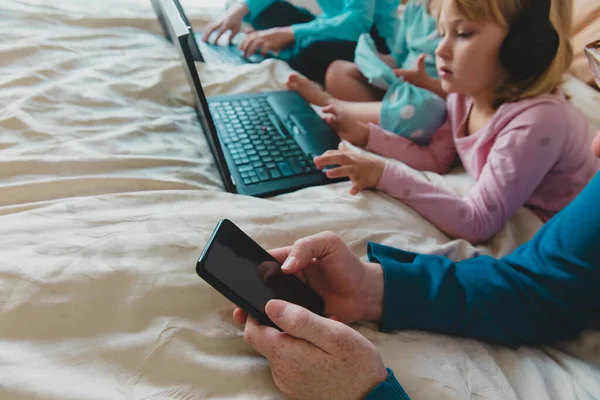 Familia quedándose en casa, padre con teléfono móvil y niños con computadoras —  Fotos de Stock