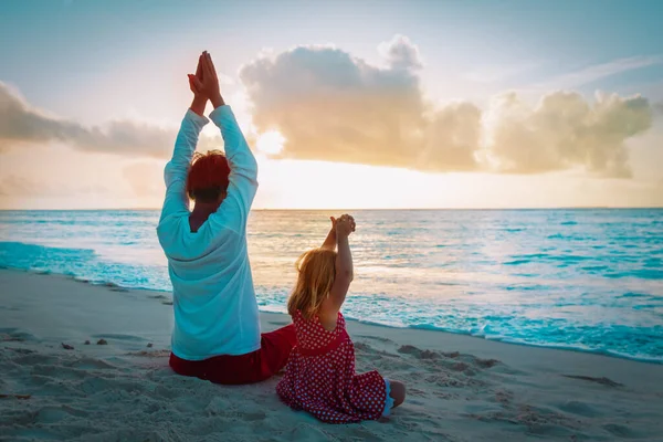 Pai e filha pequeno exercício na praia do por do sol, família fazendo ioga — Fotografia de Stock