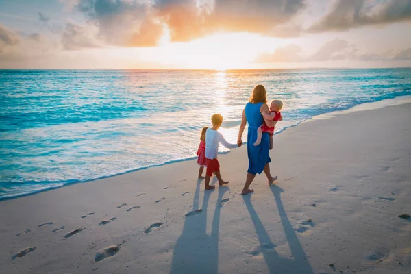 Moeder en kinderen wandelen op het strand bij zonsondergang — Stockfoto