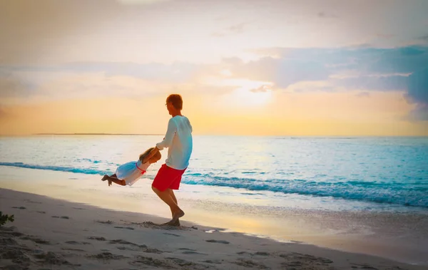 Father and little daughter play at sunset beach — Stock Photo, Image