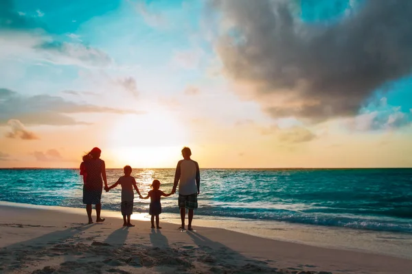 Ağaç çocukları olan mutlu aile gün batımında sahilde yürür. — Stok fotoğraf