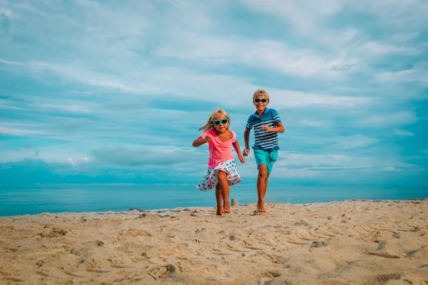 Šťastný chlapec a dívka běží na pláži, rodina se baví na moři — Stock fotografie