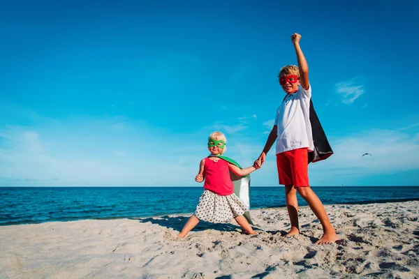 Chlapec a dívka hrát superhrdinové na pláži dovolenou — Stock fotografie
