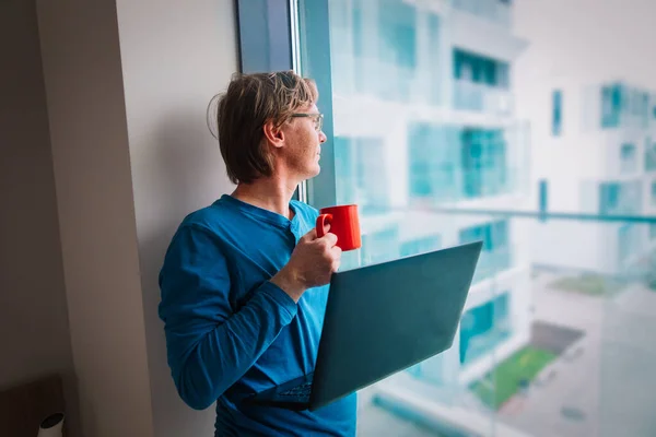 young man looking at window while staying home, remote work during quarantine