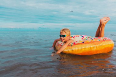 Mutlu çocuk tropik sahilde yüzüyor, çocuk denizde rahatlıyor.