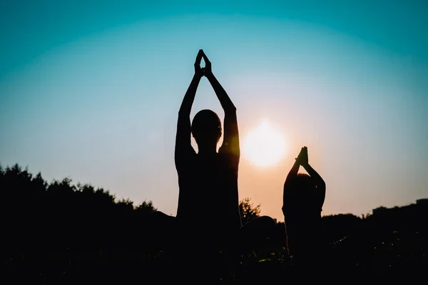 Père et petite fille faisant du yoga au coucher du soleil — Photo