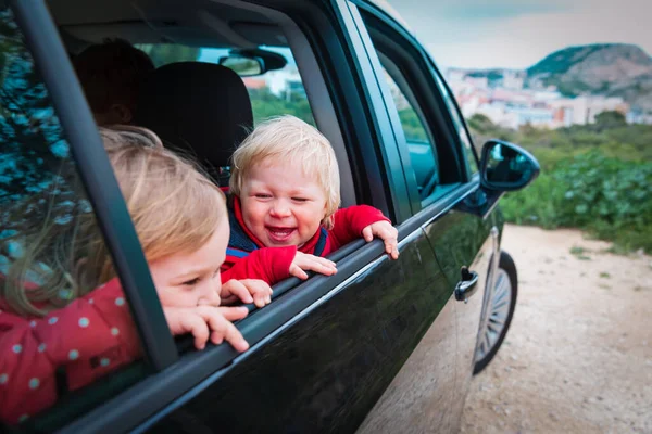 happy kids travel by car on road in nature