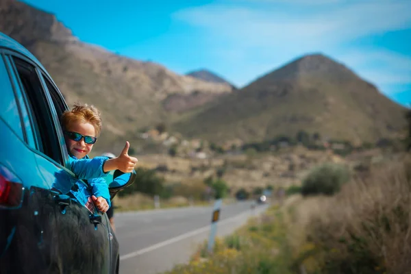 Szczęśliwy mały chłopiec cieszyć się podróżą samochodem na drodze w przyrodzie — Zdjęcie stockowe