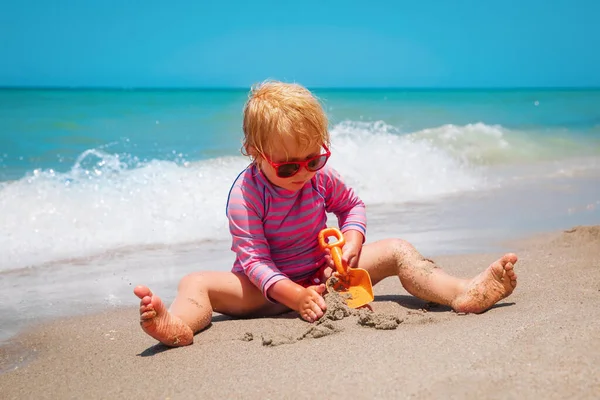 Roztomilý šťastný dívka hrát s pískem na pláži — Stock fotografie
