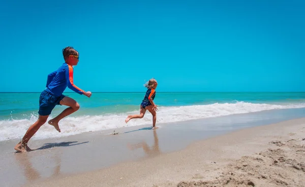 Mutlu çocuk ve kız koşup sahilde suyla oynuyorlar. — Stok fotoğraf