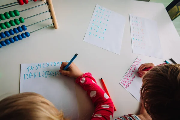 Niño y niña escribiendo números, niños haciendo la tarea — Foto de Stock