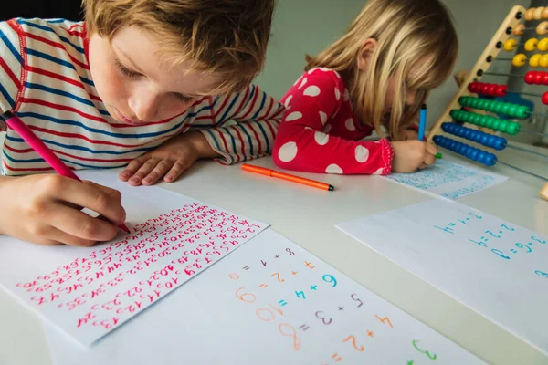 Pojke och flicka skriver nummer, barn gör läxor — Stockfoto