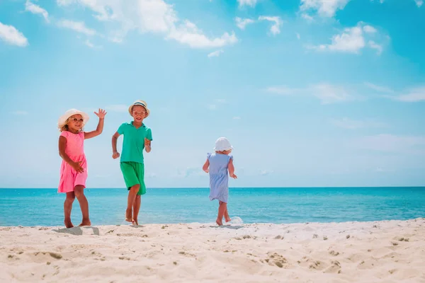 Gelukkige kinderen- jongen en meisjes- dansen op het strand, familie genieten van vakantie op zee — Stockfoto