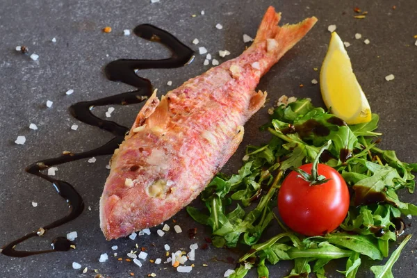 Grilled red mullet on a greay abstract background with rokka salad, balsamic glaze,lemon and cherry tomato. Healthy eating concept — Stock Photo, Image