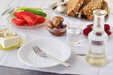 Yunan yemeği, mezedes. Kavanoz zeytin yağı ve asma sirke, zeytin, beyaz peynir, cacık, karanlık ekmek, Rakı, pancar, taze salatalık ve domates üzerinde beyaz bir arka plan ile. Sağlıklı beslenme kavramı. Sağlıklı gıda.