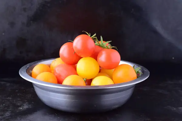 新鲜的樱桃番茄不同形状和颜色在黑色的表面上的金属碗。健康食品，健康的概念. — 图库照片