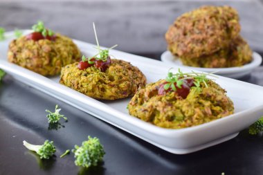 Siyah bir arka plan üzerinde taze brokoli ile beyaz tabakta domates soslu brokoli topları derin kızarmış. Sağlıklı beslenme kavramı. Diyet.