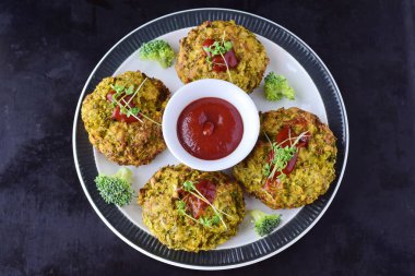 Siyah bir arka plan üzerinde taze brokoli ile beyaz tabakta domates soslu brokoli topları derin kızarmış. Sağlıklı beslenme kavramı. Diyet.