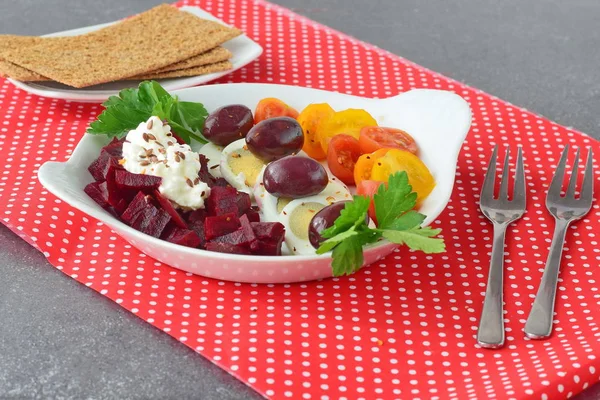 Kolay Kahvaltı: beetroots, kiraz domates, yumurta, peynir ve kraker kırmızı Tekstil arka plan üzerinde beyaz bir tabak içinde. Sağlıklı gıda kavramı