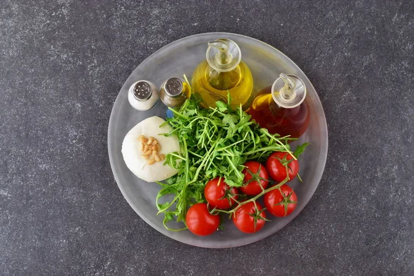 Ингредиенты для традиционного итальянского салата капрезе на стакане Трей на сером фоне с бутылками оливкового масла и винного уксуса — стоковое фото