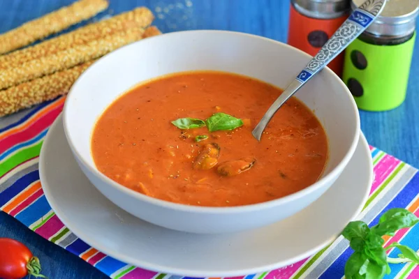 Томатный суп с мидиями в голубой миске на голубом фоне с хлебными палочками. Концепция здорового питания . — стоковое фото