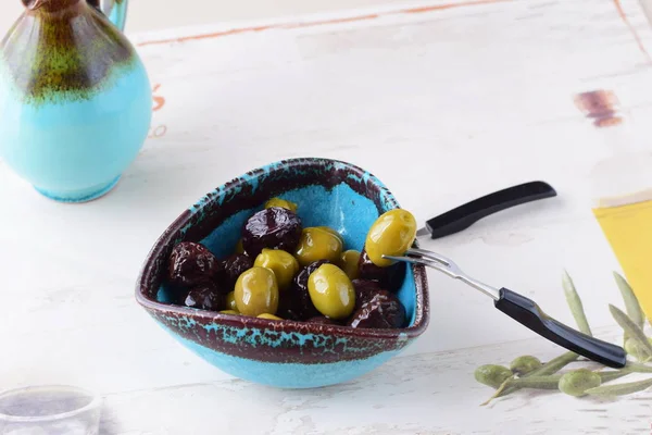 Зеленые и черные оливки в оливковом масле в традиционной греческой чаше — стоковое фото