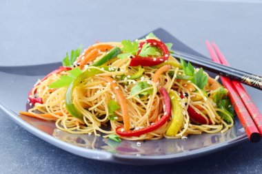 Gri bir seramik tabak erişte ve sebze üzerinde gri bir arka plan ile. Asya gıda. Sağlıklı beslenme kavramı.