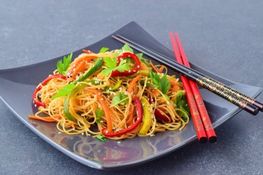 Gri bir seramik tabak erişte ve sebze üzerinde gri bir arka plan ile. Asya gıda. Sağlıklı beslenme kavramı.