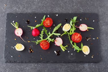 Taze turp, kiraz domates, Bıldırcın yumurta, ruccola siyah taş tabakta balsamik sır ile. Akdeniz yaşam tarzı. Sağlıklı gıda.