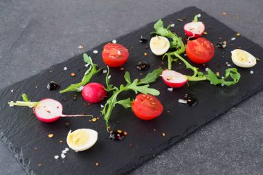 Taze turp, kiraz domates, Bıldırcın yumurta, ruccola siyah taş tabakta balsamik sır ile. Akdeniz yaşam tarzı. Sağlıklı gıda.