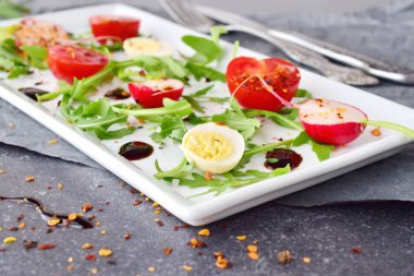 Taze turp, kiraz domates, Bıldırcın yumurta, beyaz tabakta balzamik glaze ile ruccola. Akdeniz yaşam tarzı. Sağlıklı gıda. Seçici odak.