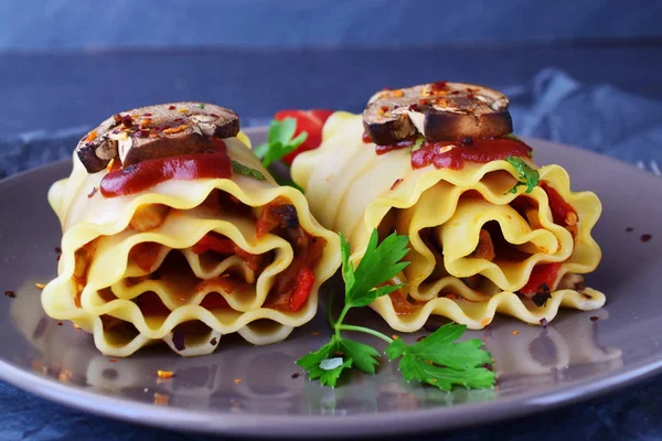 Pasta rolls with vegetables: paprika, onion, olives, mushrooms, tomato on a light brown plate on a grey abstract background. Vegetarian food. Dieting. Mediterranean lifestyle. — Stock Photo, Image