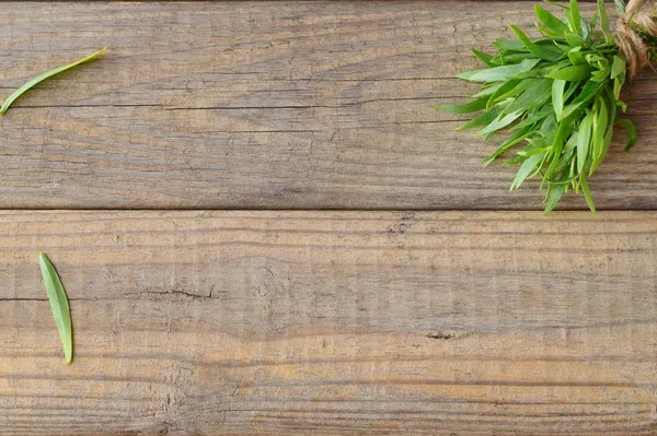 Bunch of fresh tarragon on a wooden background with a space for note. — Stock Photo, Image