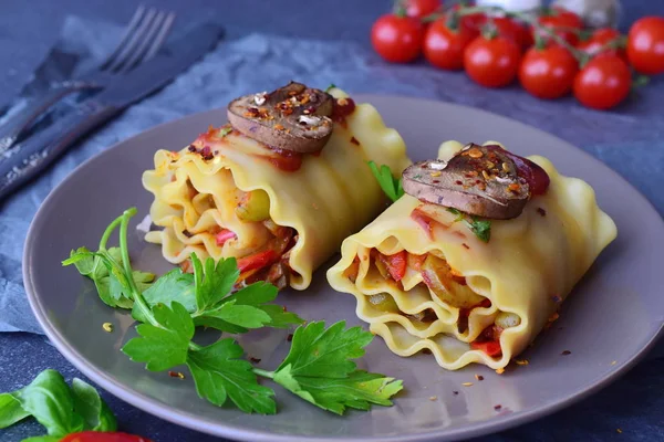 Bereit, vegetarische Lasagne in Rollen mit Pilzen, Paprika, Oliven, Tomatensauce auf einem braunen Keramikteller zu essen. Gesunde Ernährung. Vegetarische Kost. Schritt für Schritt kochen. — Stockfoto