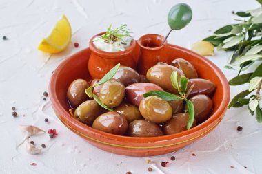 Bir geleneksel kahverengi seramik kase, tzatziki sos, sarımsak, limon ile zeytin zeytin dalı ve zeytinyağı üzerinde beyaz bir arka plan soyut.