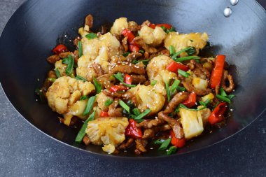 Tatlı ve ekşi sığır eti ilave edin wok karnabahar ve gri bir arka plan üzerinde sebze kızarmış. Oryantal yemek. Sağlıklı beslenme kavramı.