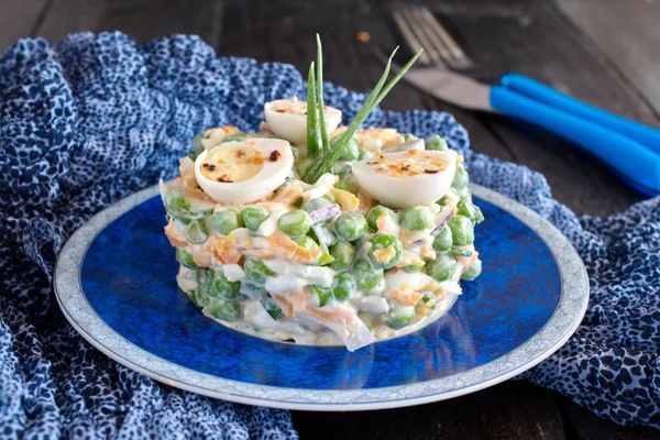 Salade à la carotte bouillie, pois, œufs, fromage et oignon rouge frais avec yaourt et ail sur une assiette bleue avec chiffon bleu sur un fond en bois . — Photo