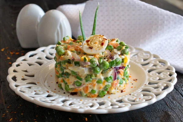 Salat mit gekochten Karotten, Erbsen, Eiern, Käse und frischen roten Zwiebeln mit Joghurt und Knoblauch auf einem weißen Teller auf einem hölzernen Hintergrund. — Stockfoto