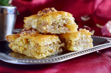 Filo hamur, şeker şurubu ve mor bez arka plan üzerinde metal kahve fincanı ile metal bir tepsi wallnuts ile yapılan geleneksel Yunan baklava.