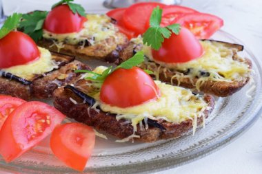 Patlıcan, peynir ve domates bir cam tabakta tost.