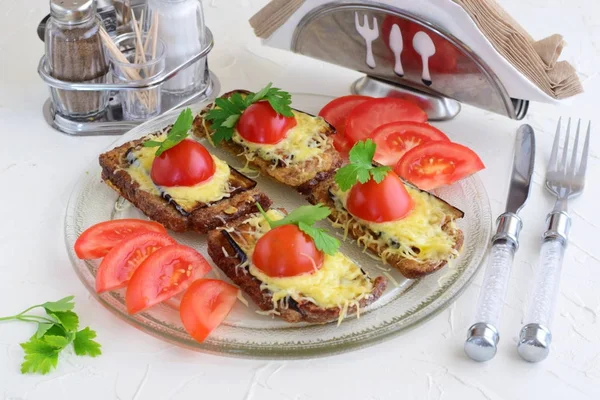 Toasts à l'aubergine, au fromage et à la tomate sur une assiette en verre . — Photo