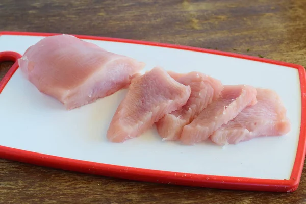 Pechuga de filete de pavo crudo cortada en rodajas en una tabla de cortar blanca — Foto de Stock