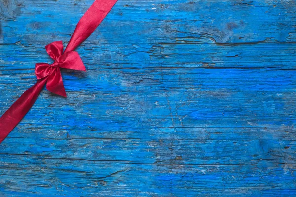 Red bow on blue wooden background — Stockfoto