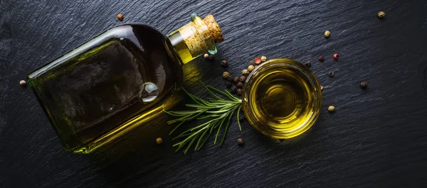 Оливковое масло в стеклянной бутылке, розмарин и перец — стоковое фото